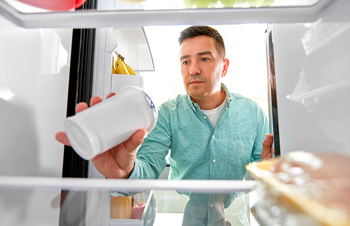 Uomo controlla la data di scadenza di un prodotto alimentare all'interno del frigorifero, valutando la sua conservazione, simbolo dell'articolo del blog food di Lifeanalytics sulla Shelf-life alimentare: come garantire durata, sicurezza e qualità