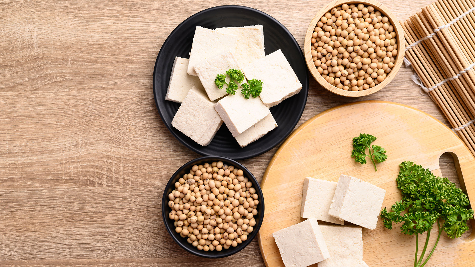 Tofu a cubetti con soia secca in ciotole su un tavolo di legno, decorato con prezzemolo fresco, simbolo del servizio Alimenti Dietetici, Plant-Based e Vegan Food