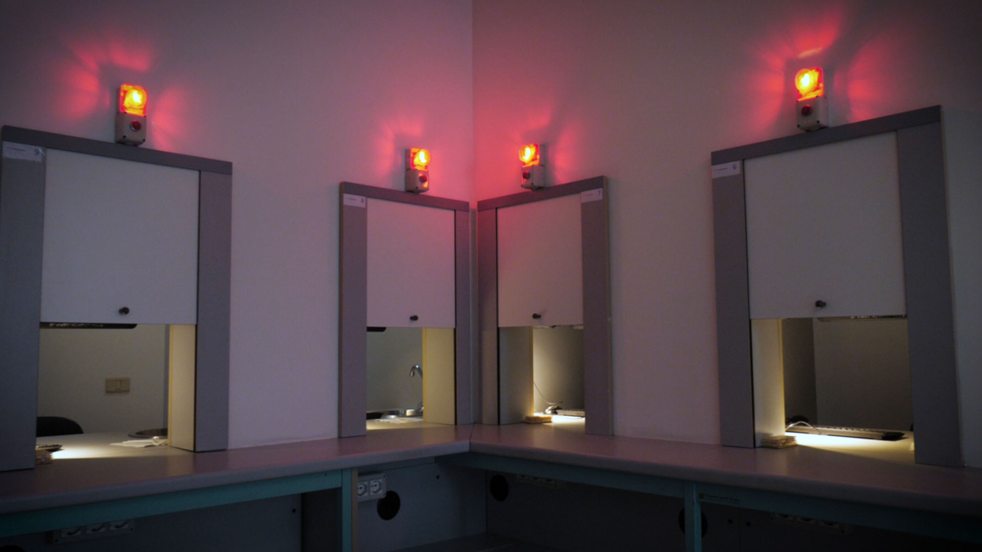 Laboratorio di analisi sensoriale con postazioni di lavoro separate da pannelli grigi, sopra ogni postazione un segnale luminoso rosso, simbolo della sala sensoriale dedicata all'analisi sensoriale