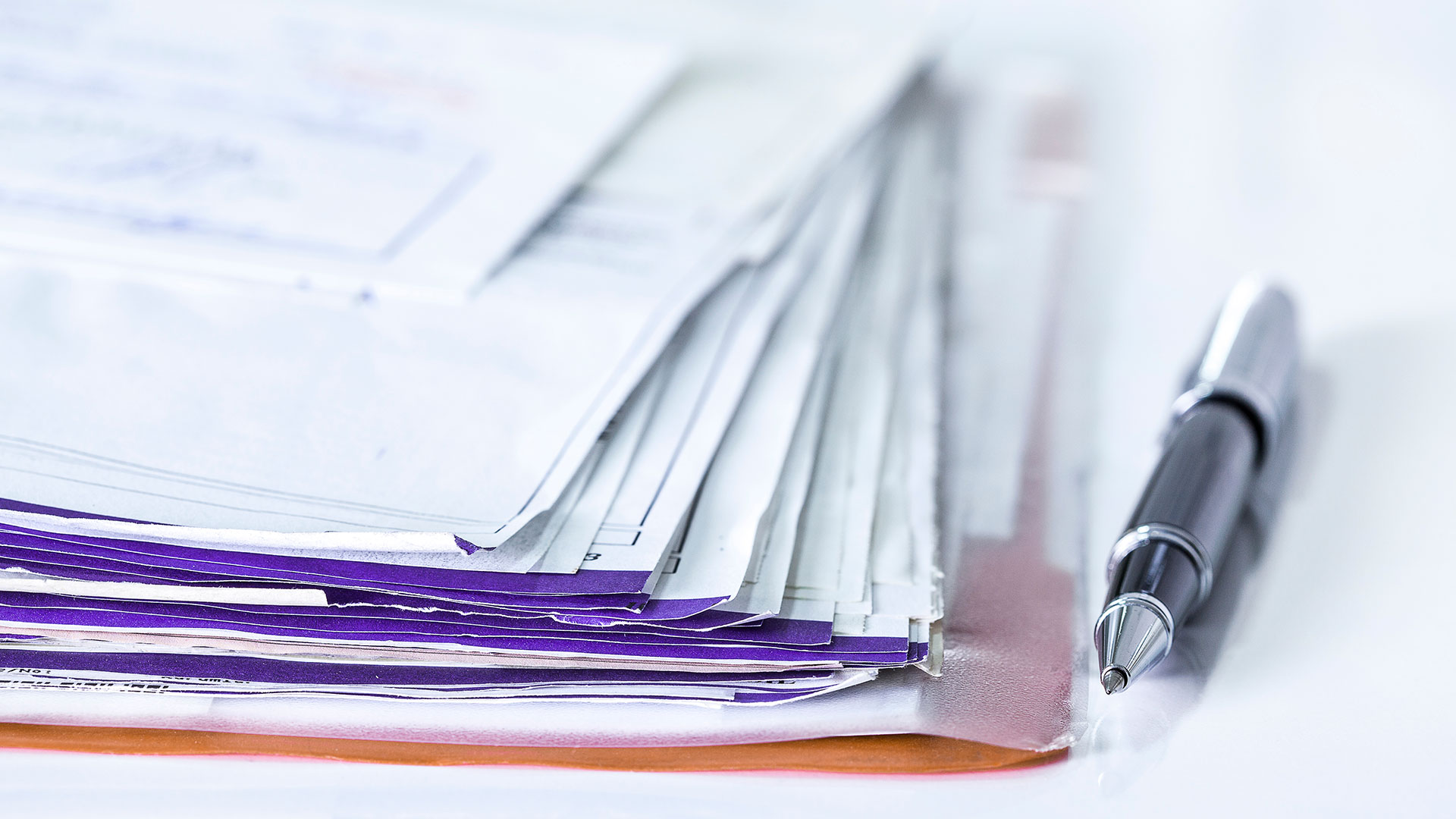 Immagine di una scrivania con vari fogli impilati ed una penna aperta, simbolo del servizio di Assessment Proposition 65 (Prop 65)