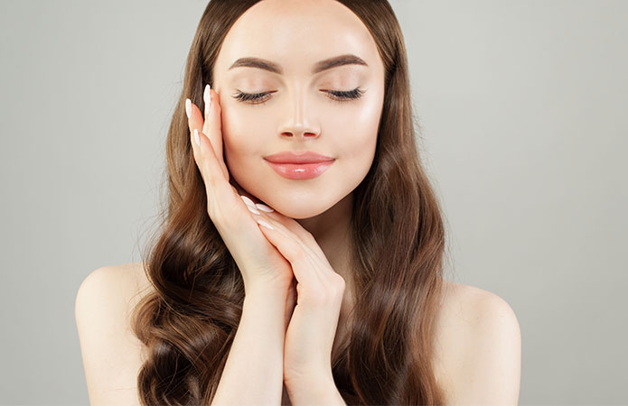 Ragazza che sfiora il volto con le mani, simbolo dell’articolo del blog dedicato ai cosmetici e integratori alimentari: come potenziare l’attività antiossidante nell’ambito della business unit cosmetic & medical device di Lifeanalytics.