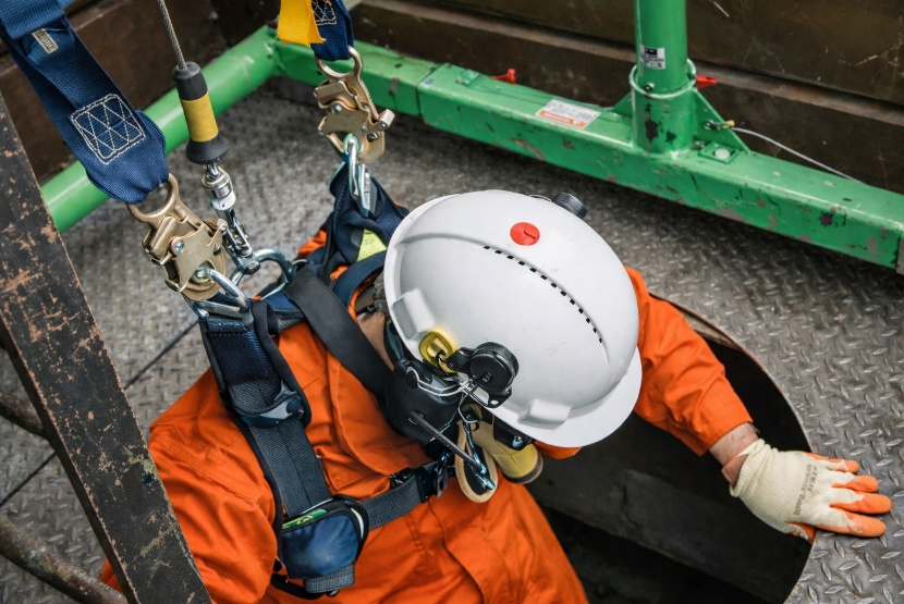 Operatore con casco e imbracatura di sicurezza che scende in uno spazio confinato tramite sistema anticaduta, simbolo dell’articolo dedicato agli spazi confinati, formazione e responsabilità della business unit EHS