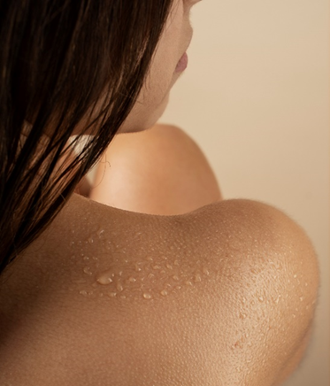 Primo piano macro della spalla e del collo di una persona con pelle luminosa, su cui sono visibili piccole gocce trasparenti di gel cosmetico o siero idratante, simbolo dell’articolo del blog dedicato alla dermocosmesi più efficace, comprendere la pelle al meglio per migliorare l’efficacia nell’ambito della business unit cosmetic & medical device di Lifeanalytics