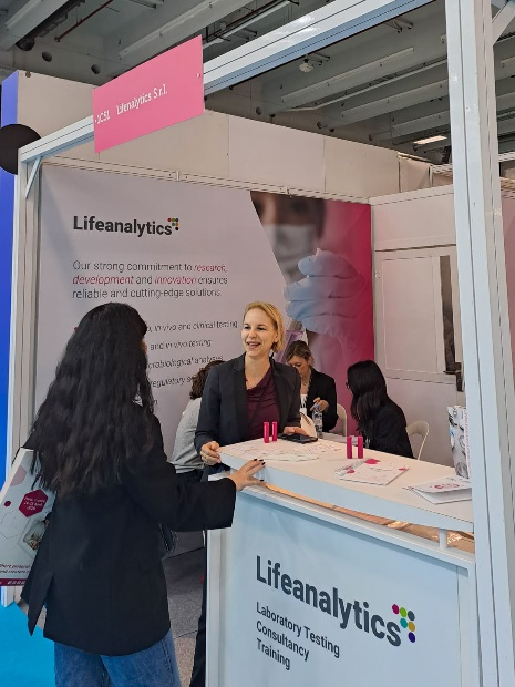 Immagine di due persone in piedi durante il momento dell'accoglienza di visitatori in fiera al desk, simbolo dell’articolo del blog dedicato alla fiera Lifeanalytics a in-Cosmetics Global 2026: direzioni future nell’ambito della business unit cosmetic & medical device di Lifeanalytics