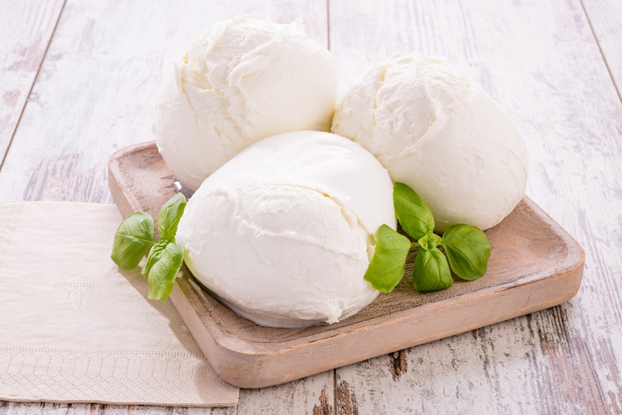 Mozzarella fresca italiana di bufala campana DOP su vassoio di legno con foglie di basilico, formaggio fresco tipico della tradizione casearia, immagine simbolo del prodotto segnalato per non conformità per errori nei dati di tracciabilità (numero di lotto e data di scadenza errati)