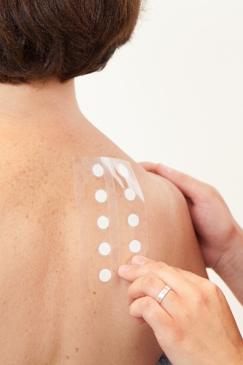 Immagine di una donna di schiena con path test applicati da una mano esterna, simbolo dell’articolo del blog dedicato ai test clinici nel makeup: un vantaggio competitivo perchè sono fondamentali per i brand beauty, della business unit cosmetic & medical device di Lifeanalytics