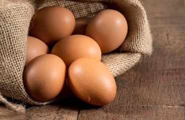 Immagine di un gruppo di uova dentro un panno di yuta sopra un tavolo di legno, simbolo dell'allerta per possibile presenza di Salmonella e Salmonella Enteritidis, confermando la necessità di rigorosi controlli lungo la filiera avicola