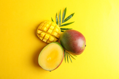 Immagine di mango interi e tagliati su sfondo giallo, simbolo di segnalazione per presenza di carbendazim oltre i limiti di legge