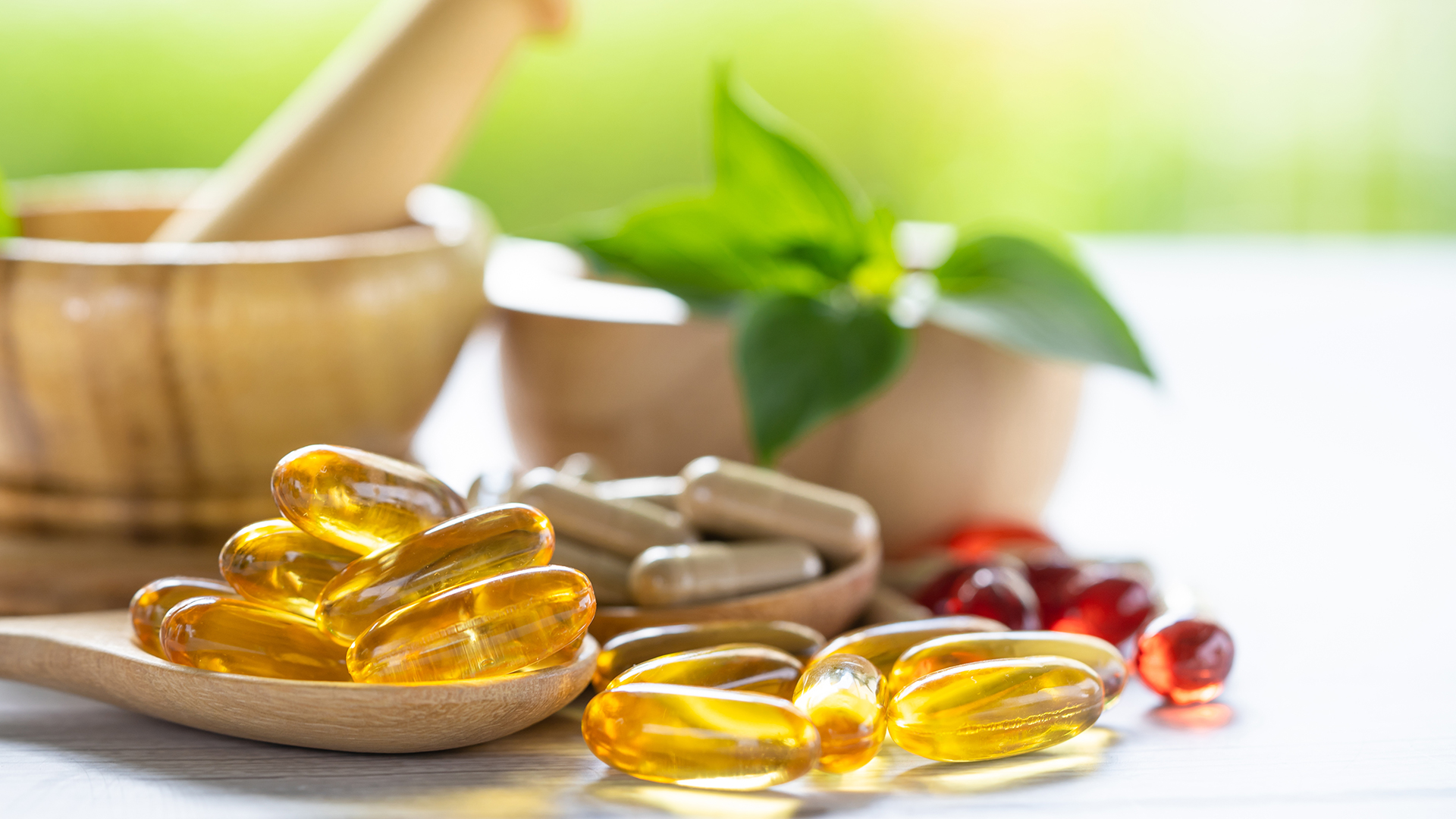 Capsule e integratori alimentari naturali con mortaio in legno ed erbe fresche sullo sfondo, simbolo del servizio food baby food, novel food e integratori alimenti di Lifeanalytics