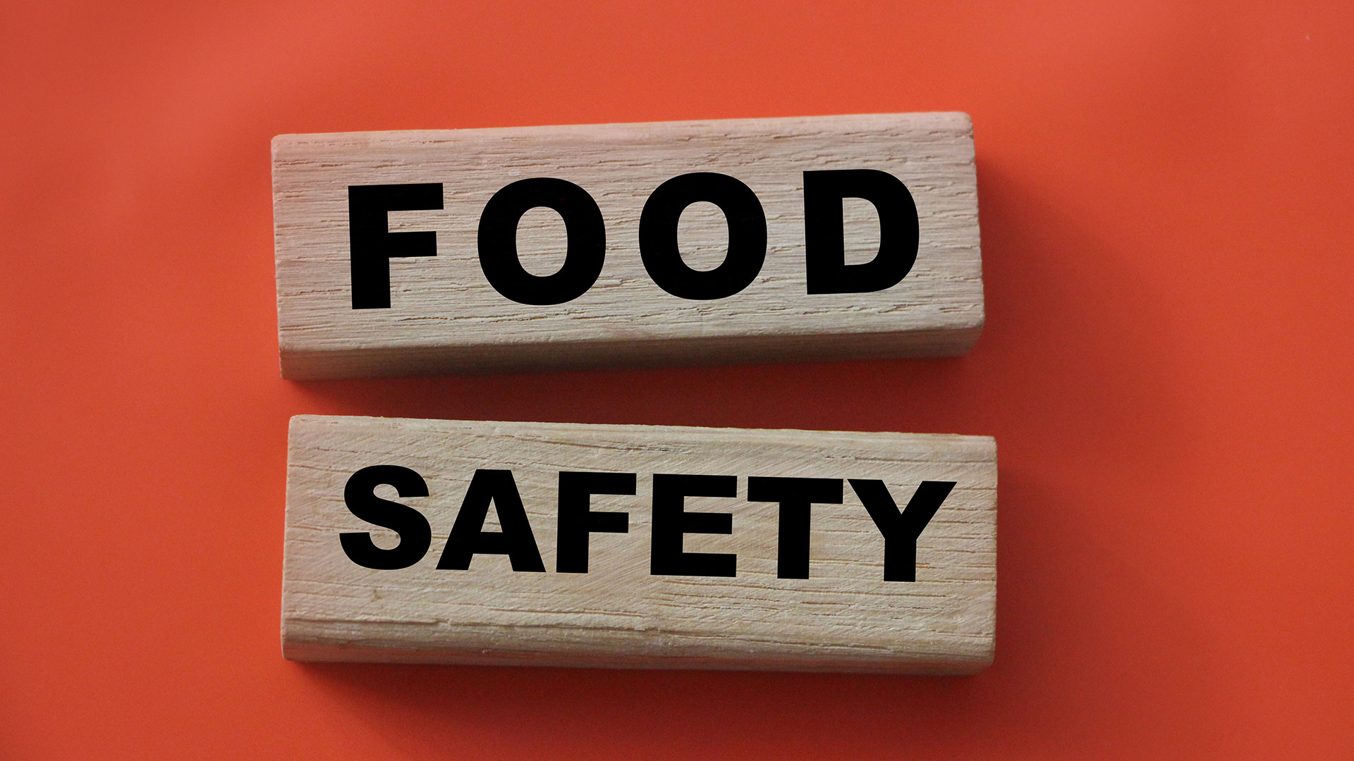 Immagine di due pezzi di legno con sopra stampate le parole food e safety su uno sfondo arancione, simbolo del servizio dedicato al supporto completo alla conformità per il mercato USA