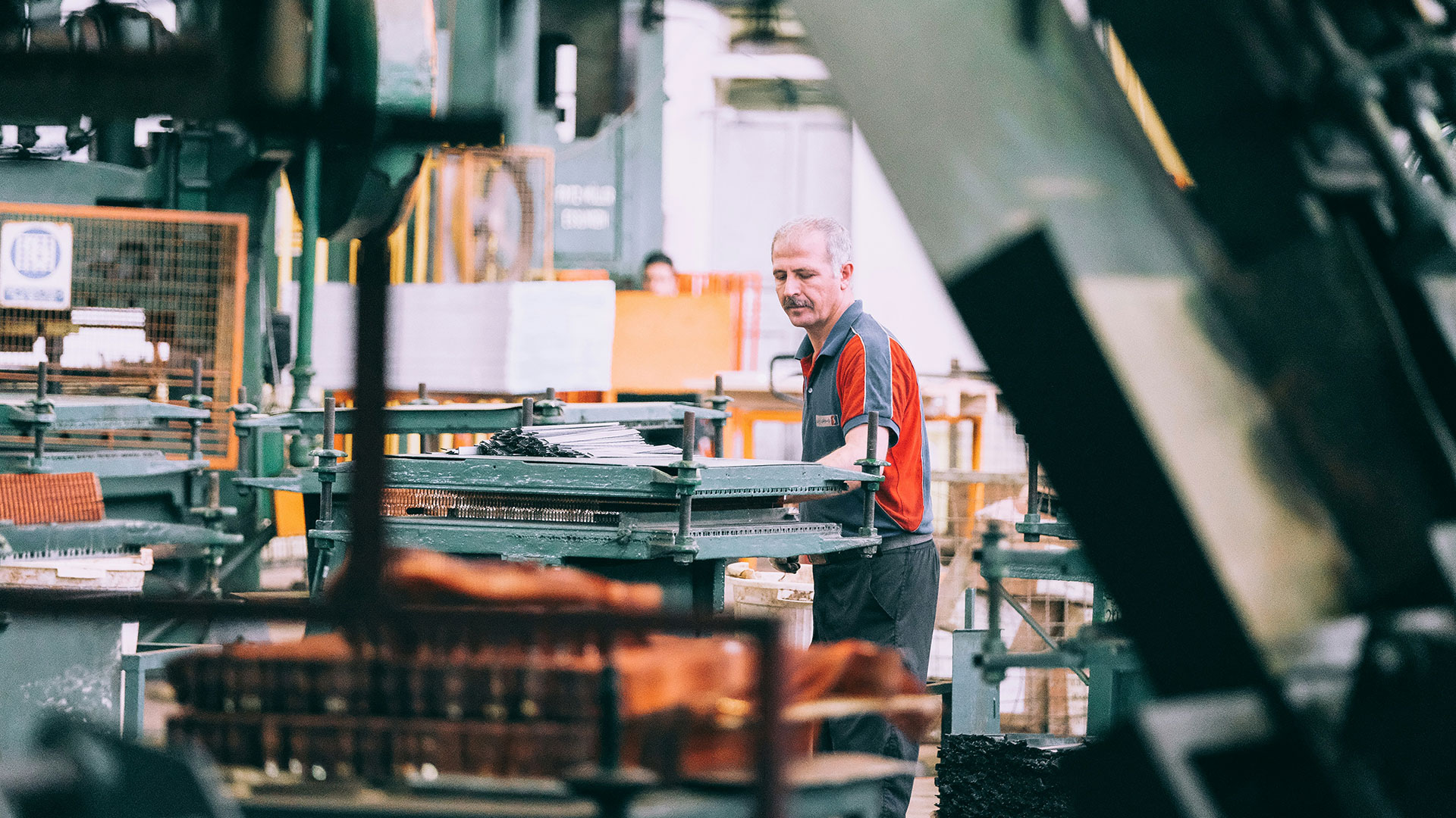 Operaio che controlla un macchinario in fabbrica industriale dove è necessaria una valutazione del rischio ergonomico