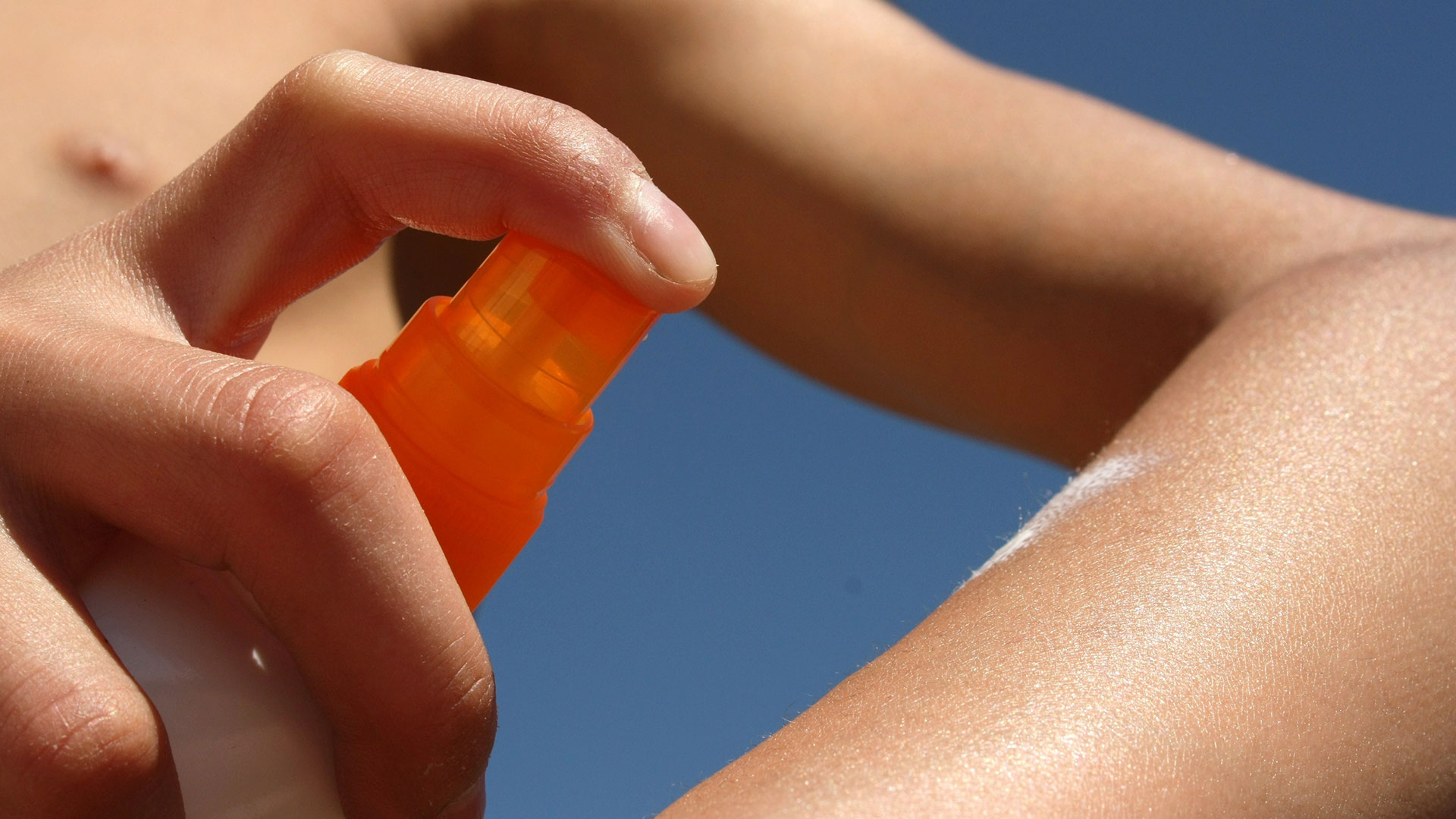 Applicazione di crema solare spray su pelle esposta al sole, simbolo del servizio Suncare della business unit cosmetic and medical device di Lifeanalytics