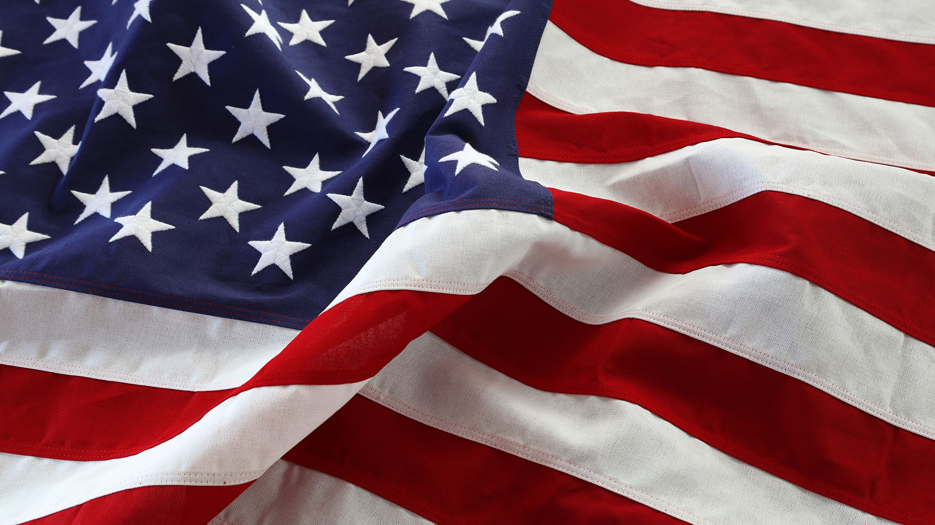 Immagine della bandiera americana con stelle e strisce al vento con increspature del tessuto, simbolo del servizio di stesura tabelle nutrizionali USA e Canada