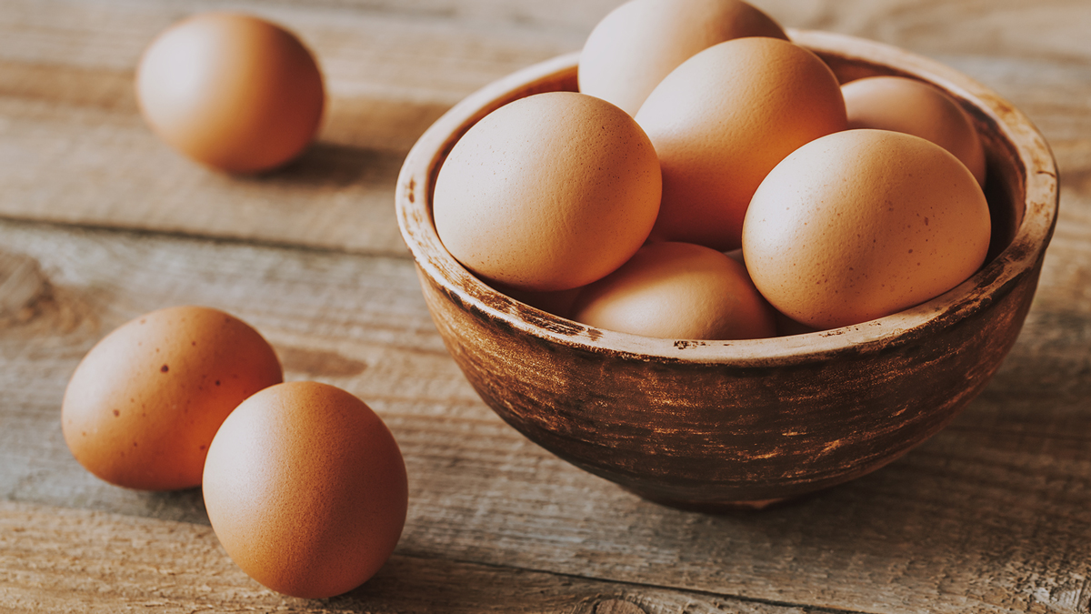 Ciotola rustica piena di uova marroni su un tavolo di legno, con alcune uova sparse intorno, simbolo del servizio Caffè, olio, uova, cacao e grassi alimentari della business unit food di Lifeanalytics