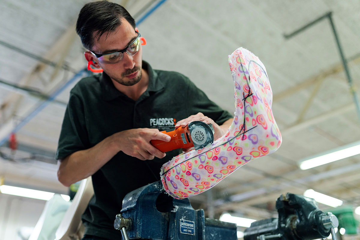 Lavoratore che utilizza un utensile elettrico per lavorare su un oggetto colorato, indossando protezioni per gli occhi in un ambiente industriale