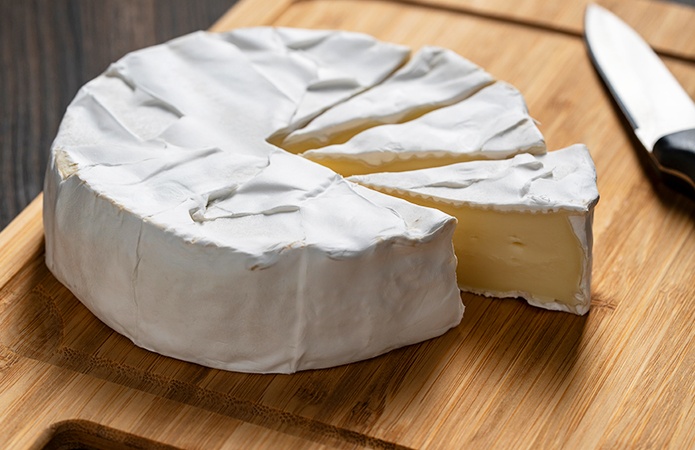 Formaggio a pasta molle su tagliere, potenzialmente a rischio di contaminazione da STEC se prodotto con latte crudo, simbolo dell'articolo del blog che tratta la tematica del Escherichia coli produttore di Shiga tossine  nei formaggi, relativo alla business unit food di Lifeanalytics