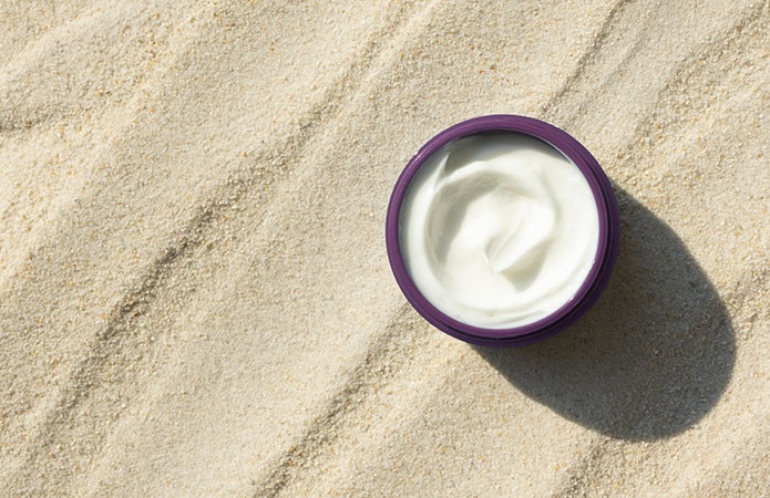Vasetto di crema cosmetica su sabbia illuminata dal sole, simbolo dell’articolo del blog dedicato all’idratazione della pelle, alla protezione cutanea e alla cura della pelle nell’ambito della business unit cosmetic & medical device di Lifeanalytics.
