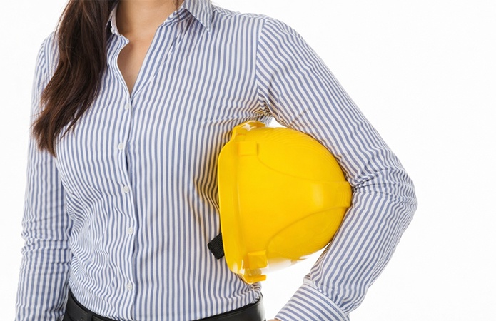Professionista con camicia a righe che tiene in mano un casco di sicurezza giallo, immagine simbolica dell’articolo della business unit EHS sul Nuovo ASR 2025 e sulle scadenze da pianificare entro maggio 2026