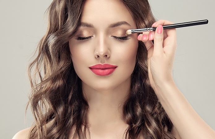 Immagine di un primo piano di una donna con trucco professionale mentre applica l'ombretto con un pennello, simbolo dell’articolo del blog dedicato ai test clinici nel makeup: un vantaggio competitivo perchè sono fondamentali per i brand beauty, della business unit cosmetic & medical device di Lifeanalytics