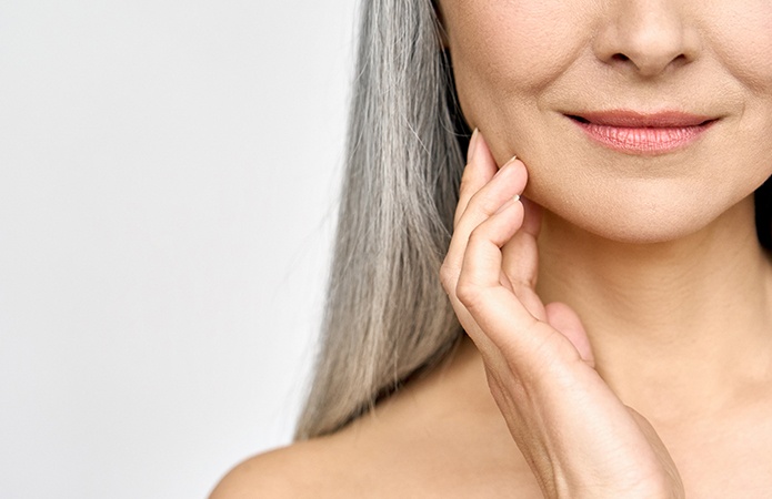 Donna in età matura che sfiora delicatamente il viso, simbolo dell’articolo del blog dedicato ai cambiamenti della pelle durante la menopausa, alla validazione scientifica dell’efficacia dei cosmetici attraverso test in vitro e in vivo e ai servizi della Business Unit Cosmetic & Medical Device di Lifeanalytics