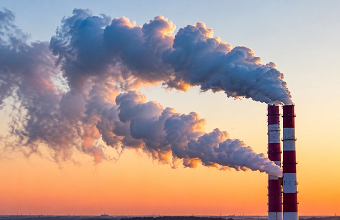 Ciminiere di un impianto industriale con emissioni diffuse nell’atmosfera, immagine simbolica dell’articolo dedicato alla gestione delle emissioni odorigene, alla valutazione dell’impatto olfattivo, alle strategie di monitoraggio e alla conformità al D.Lgs. 152/2006 e al Decreto MASE n. 309/2023 della business unit EHS